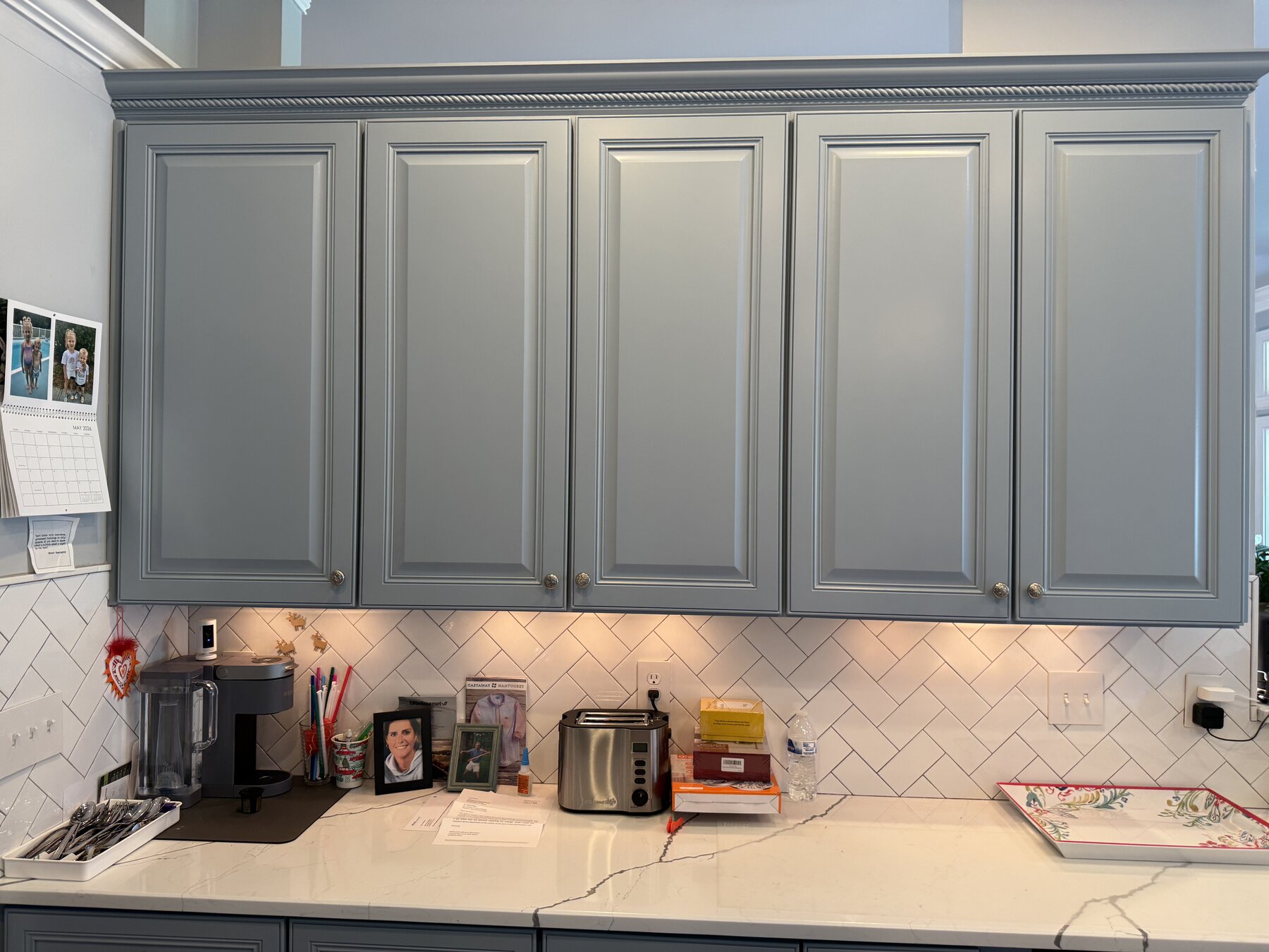 Sage green kitchen cabinets with gold hardware and patterned tile backsplash